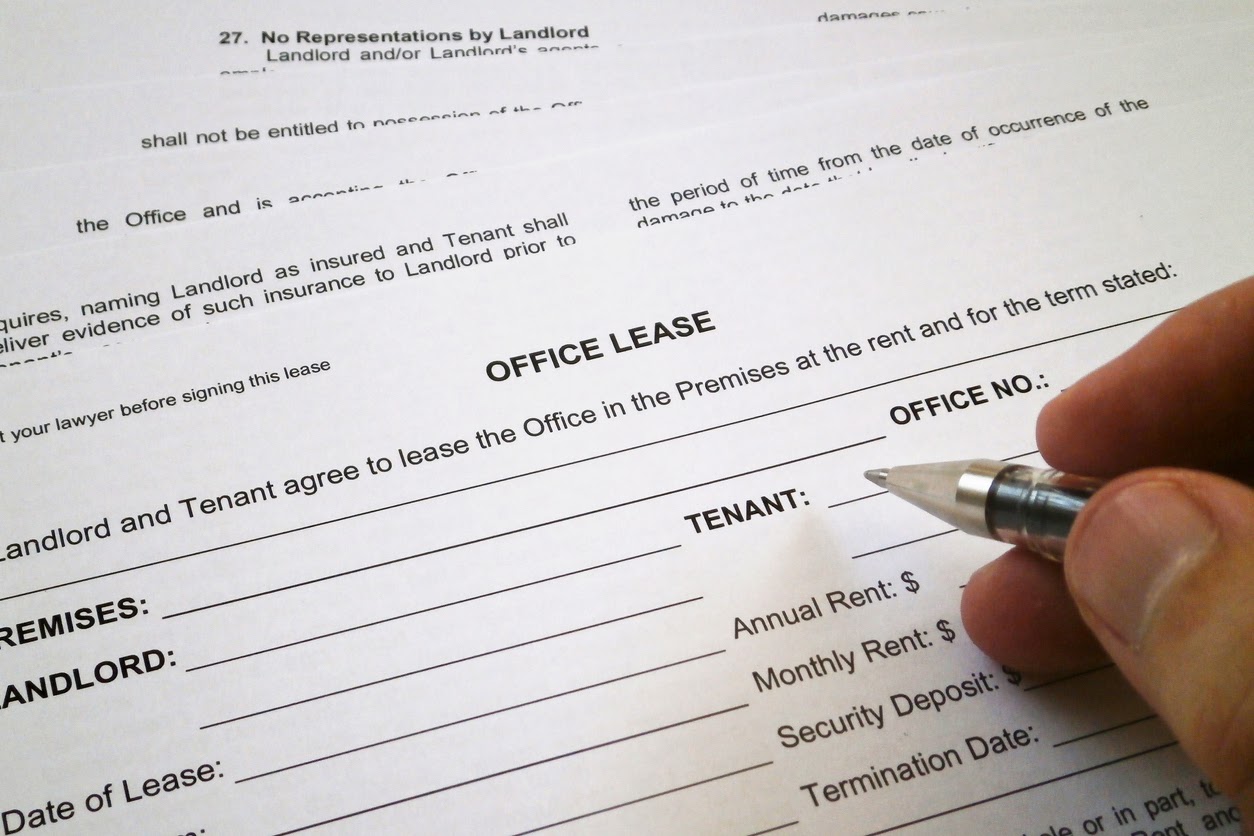 Close-up shot of a hand filling out a rental agreement for subletting office space.
