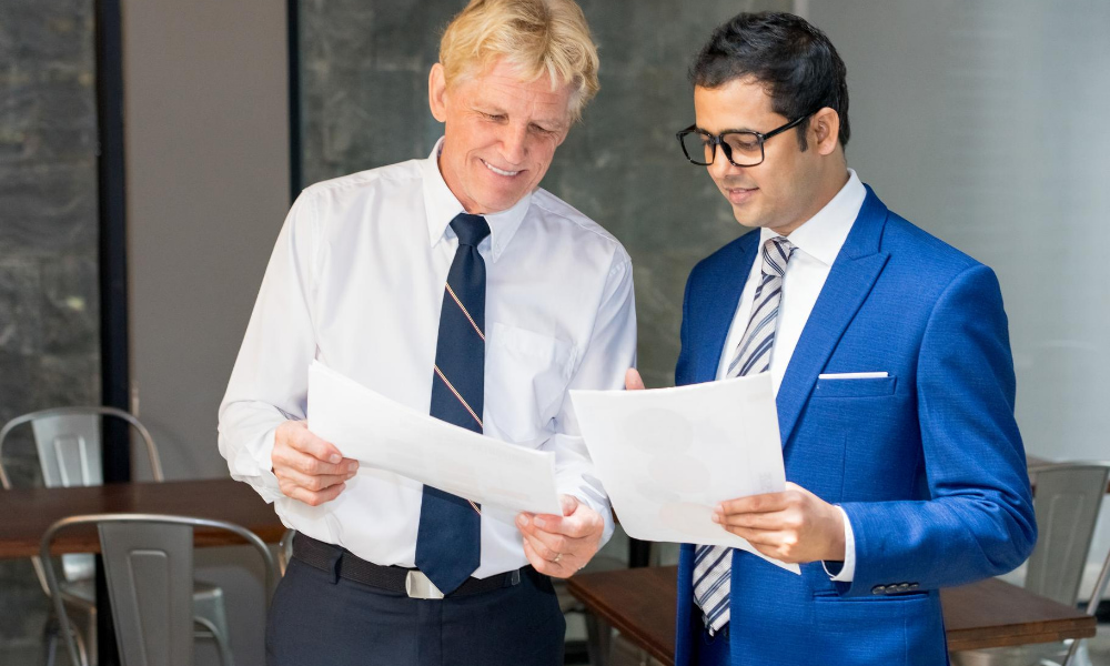 How to Conduct an In-Depth Commercial Lease Audit-The-Genau-Group Two businessmen reviewing the contract that reviews a commercial lease audit.